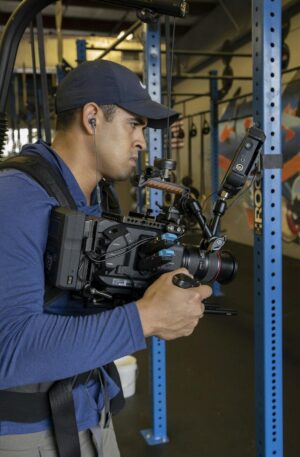 A videographer captures footage in a graffiti-adorned gym, focusing on dynamic scenes.