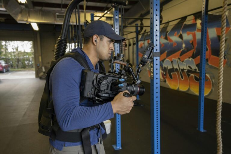 A videographer captures footage in a graffiti-adorned gym, focusing on dynamic scenes.
