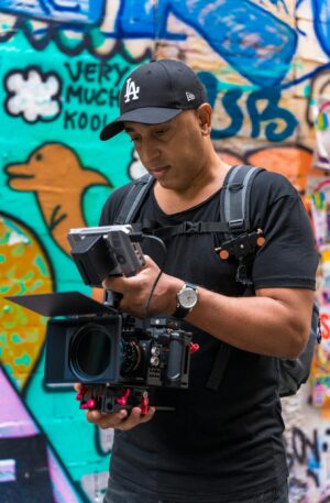 Filmmaker capturing urban graffiti scenes with professional camera equipment.